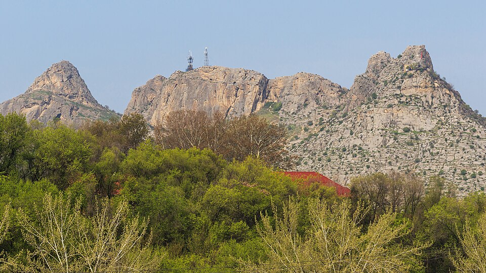Los picos rocosos de la montaña Sulaimán sobre los árboles de Osh