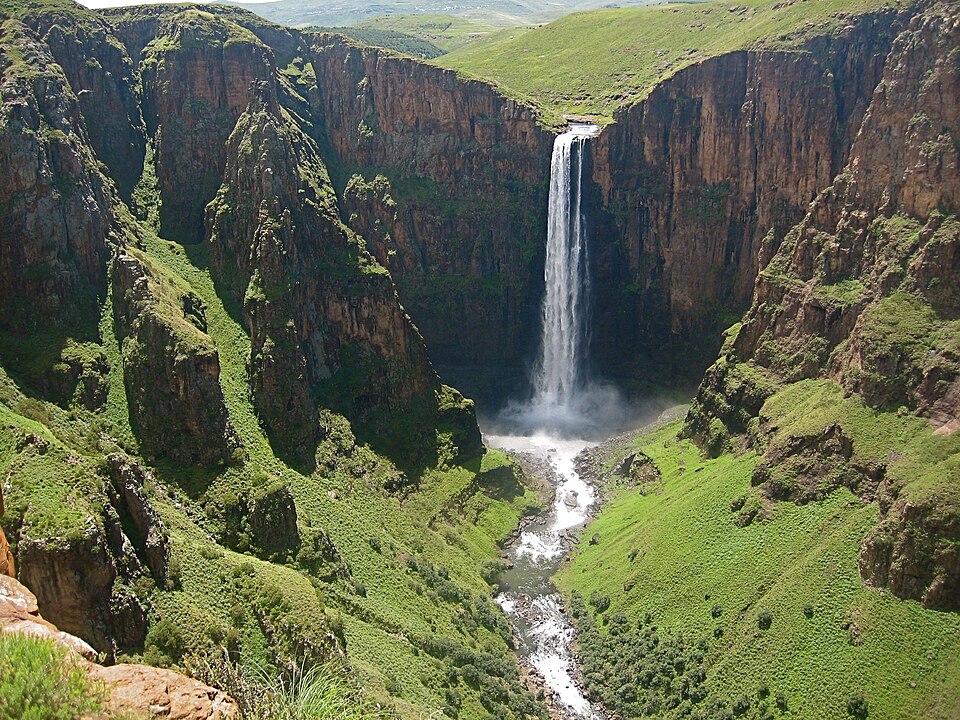 Cascada alta y delgada que cae en un cañón de paredes verdes