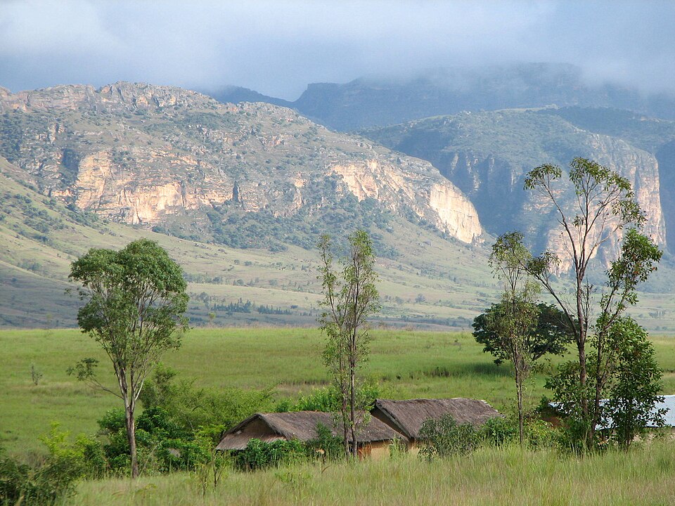 Macizo de arenisca con acantilados y pradera verde con árboles en Isalo