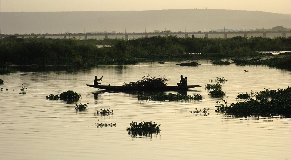 Piragua sobre el río Níger en Bamako al atardecer, con el puente al fondo