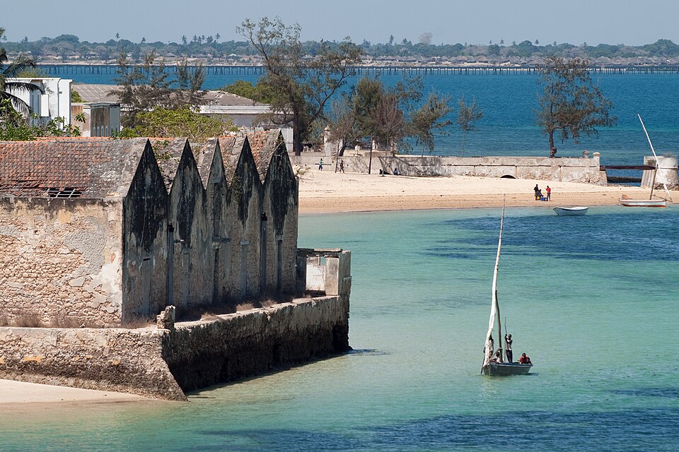 Casas antiguas de la Isla de Mozambique junto al agua turquesa con un dhow de vela