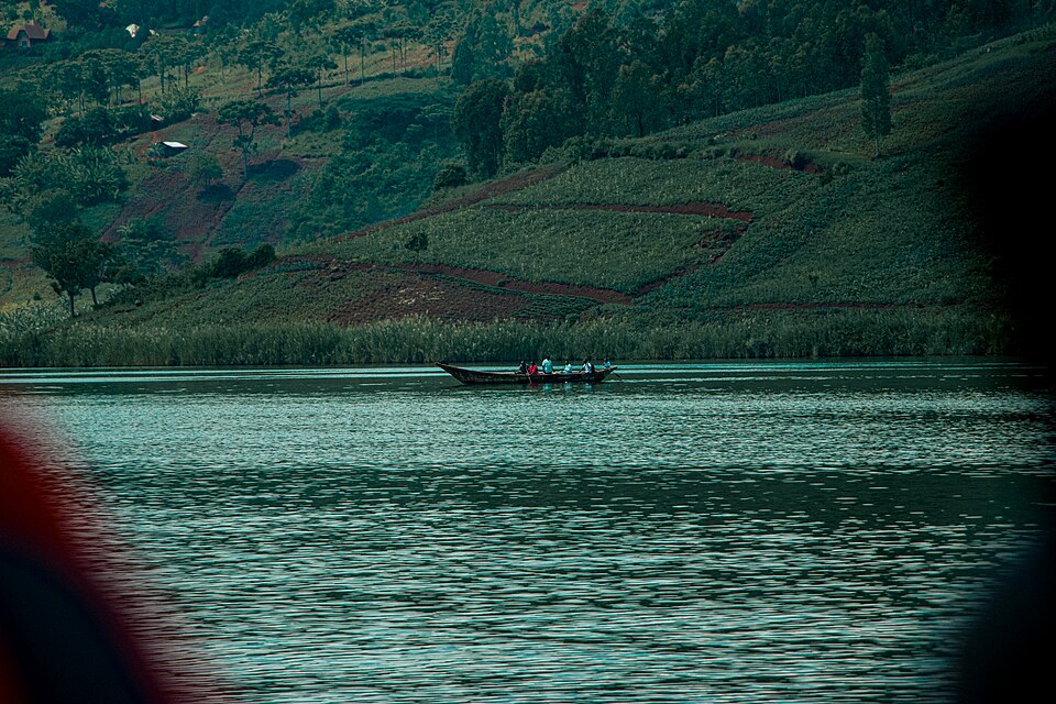 Piragua en el lago Kivu con laderas verdes cultivadas al fondo