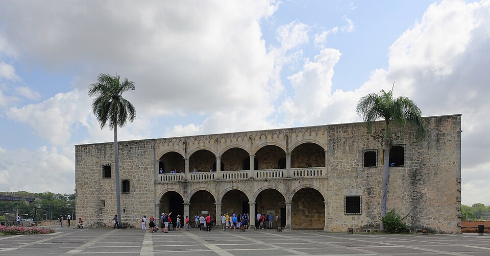 El Alcázar de Colón, palacio de piedra con dos pisos de arcadas, y palmeras