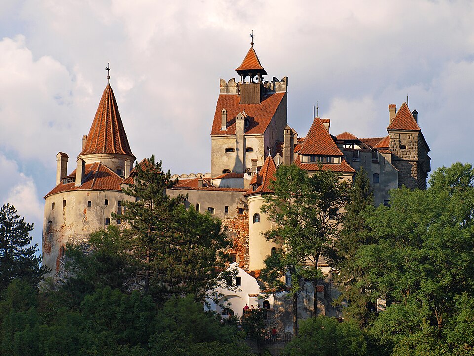El castillo de Bran con sus torres rojas entre árboles