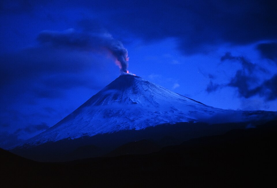 Un volcán de Kamchatka nevado en erupción al anochecer