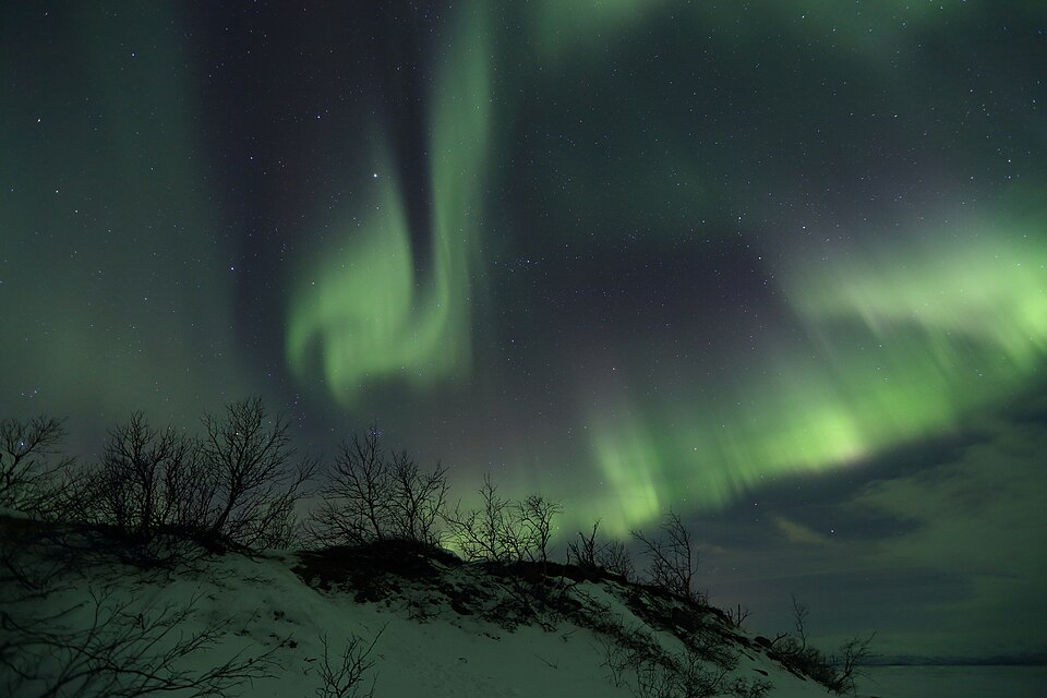 Una aurora boreal verde sobre la nieve en Abisko