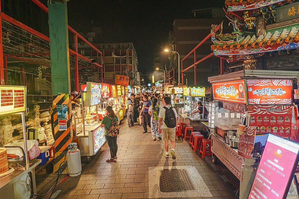 Puestos de comida iluminados en el mercado nocturno de Shilin