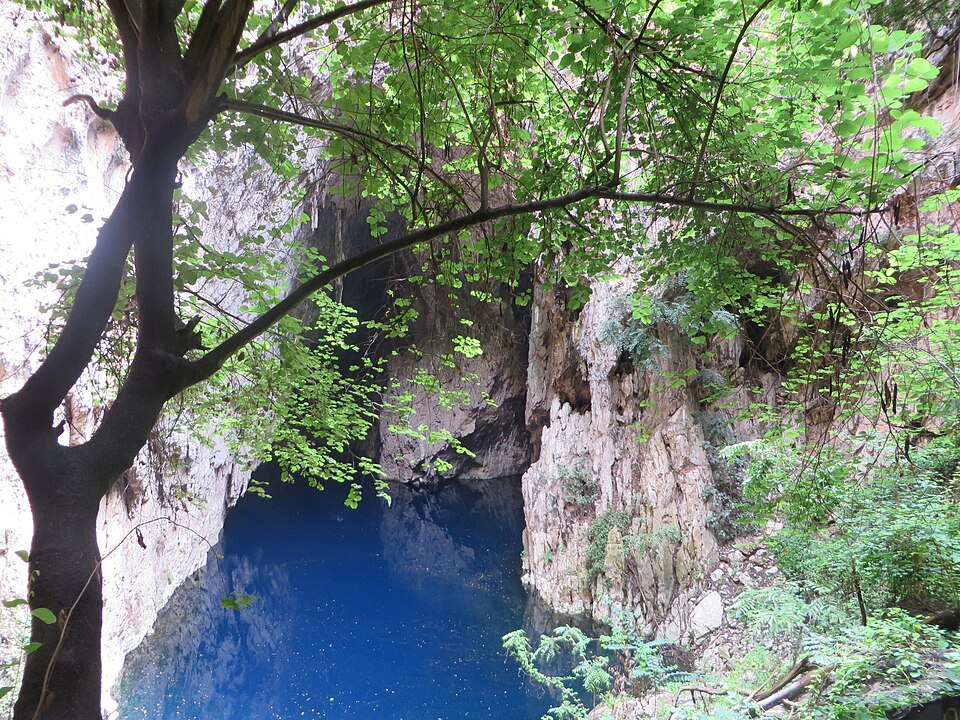 Poza de agua azul intenso en el fondo de la cueva de Chinhoyi entre árboles