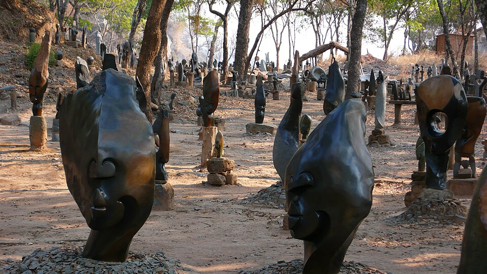 Cientos de esculturas de piedra oscura entre árboles en Tengenenge